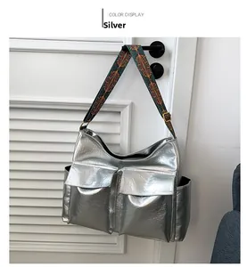 Detail of silver tote bag with metallic sheen and colorful ethnic geometric strap