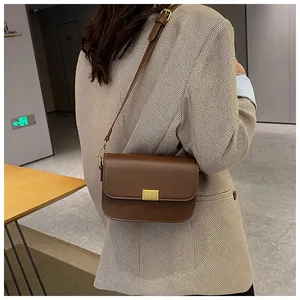 Brown leather crossbody bag with gold buckle detail shown on model in blazer