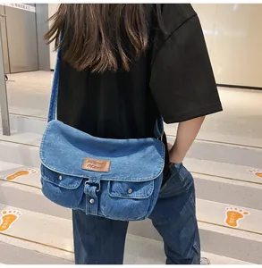 Close-up of vintage blue denim crossbody bag featuring dual front snap pockets and flap