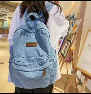 Rückansicht eines hellblauen Jeans-Rucksacks mit braunem Logo an einem weiblichen Model