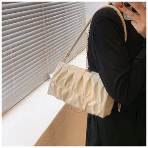 Detailansicht der cremeweißen Falten-Cloud-Tasche mit Goldkette und Lederriemen