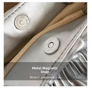Close-up of the silver metallic leather texture and magnetic snap on the pleated handbag