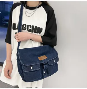 Detail of vintage blue denim messenger bag with two front pockets and leather logo patch