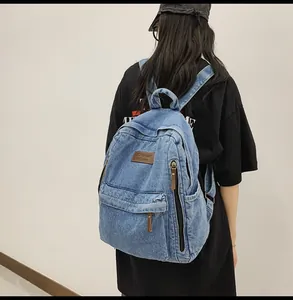 Detail of blue denim backpack with leather label and textured wash finish for daily use