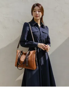 Sac fourre-tout en cuir marron avec anses marron foncé et bandoulière sur un mannequin