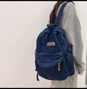 Detail eines dunkelblauen Denim-Rucksacks mit braunem Lederlogo und stabilen Schultergurten