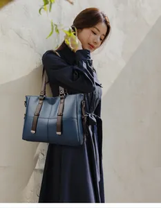 Vue détaillée du sac cabas bleu foncé avec anses en cuir marron et boucle métallique