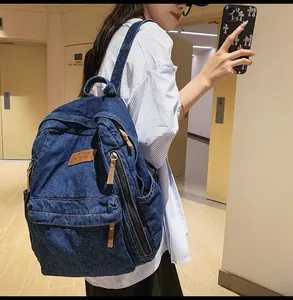 Detail of blue denim backpack with brown leather patch and adjustable shoulder straps