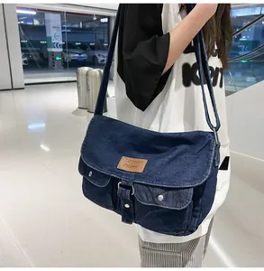 Close-up of deep blue denim crossbody bag featuring dual front pockets and contrast stitching