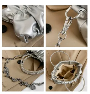 Detail view of silver pleated cloud bag featuring rhinestone handle and metallic chain