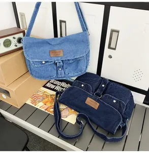 Detail of light blue and navy denim messenger bags with double pockets on white lockers