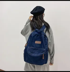 Detail eines dunkelblauen Denim-Rucksacks mit braunem Lederlogo-Patch und robustem Metallreißverschluss