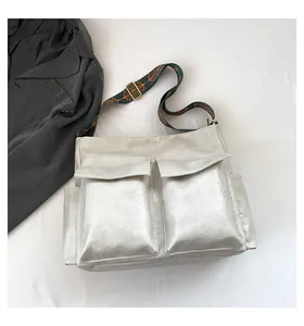 Detail of vintage silver tote bag featuring dual front pockets and ethnic patterned strap