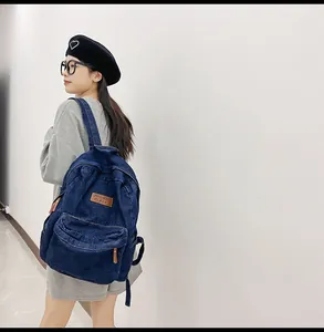 Detaillierte Seitenansicht des marineblauen Denim-Rucksacks mit Lederaufnäher und Reißverschluss