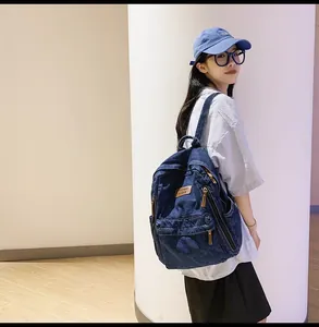 Detail of blue denim backpack with metal zipper, brand logo patch and matching cap