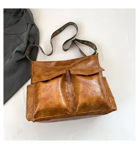 Detail of vintage brown leather bag with dual front pockets and ethnic wide shoulder strap