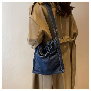 Detailed close-up of dark blue denim tote bag texture and reinforced shoulder strap stitching