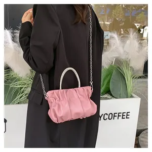 Detail of pink pleated cloud bag with rhinestone handle on black coat background