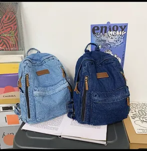 Detail view of denim backpacks in light and dark blue with premium leather zip pullers