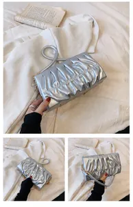 Detail der silbernen Falten-Tasche mit Metallic-Struktur, Rundgriff und goldener Kette