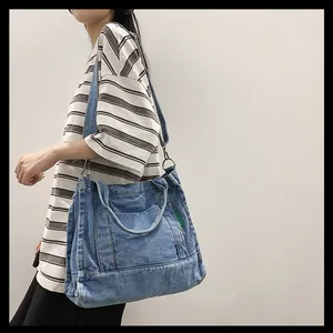 Detail of blue washed denim tote bag showing metal ring clasp and green woven label