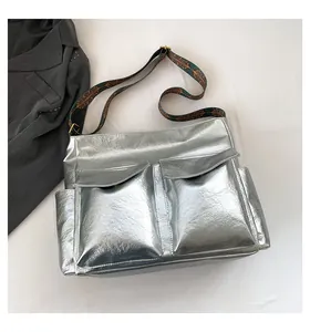 Close-up of metallic silver tote bag featuring utility pockets and woven jacquard strap