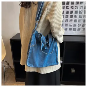 Detail of washed denim tote bag with metal ring handle and rivet reinforced side pockets