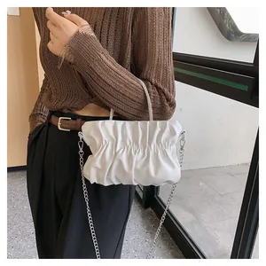 Detail of white pleated cloud bag featuring sparkling rhinestone handle and chain strap