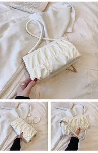 Detailansicht der weißen Rafftasche mit goldener Kette und eleganten Faltenstrukturen