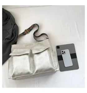 Detail of silver metallic messenger bag with large front pockets and ethnic woven strap