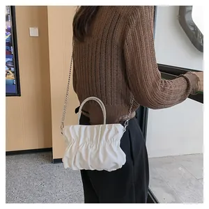 Detailed view of white pleated cloud bag featuring a luxury rhinestone encrusted handle