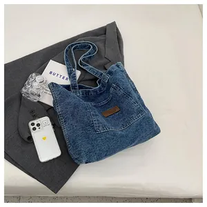 Close-up of blue denim tote bag with textured fabric surface and brown leather label
