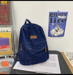 Detail eines dunkelblauen Denim-Rucksacks mit braunem Lederpatch und Metallreißverschluss