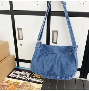Detail of blue washed denim messenger bag with adjustable strap and stitching