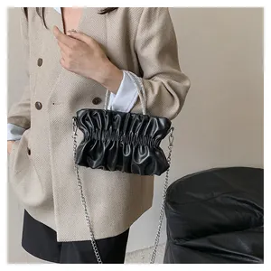 Detail of elegant black pleated cloud bag with shiny rhinestone handle and silver chain strap