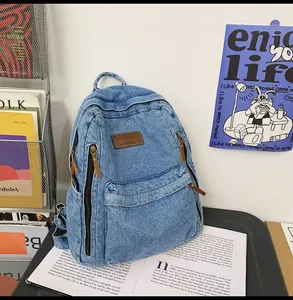 Detail of blue denim backpack with brown leather logo patch and multiple zipper pockets
