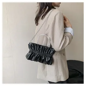 Detail of black ruched leather bag featuring elegant rhinestone handles and silver chain