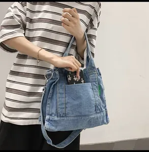 Detail of blue denim tote bag showing front pocket and interior space for a smartphone