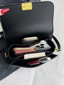 Minimalist black leather crossbody bag with gold hardware and spacious interior view