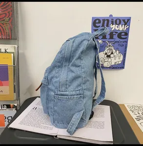 Detailansicht des Denim-Rucksacks mit Leder-Reißverschluss auf hellblauem Baumwollstoff