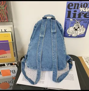 Detail view of denim backpack back with adjustable straps and washed blue fabric texture