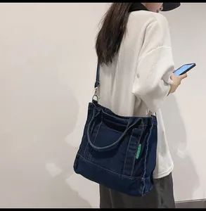 Detail of dark blue denim tote bag featuring side pockets and adjustable shoulder strap