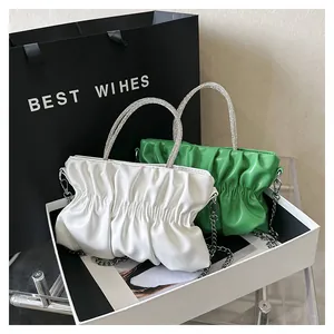 Detailed view of cloud pleated handbag with rhinestone handles in white and green