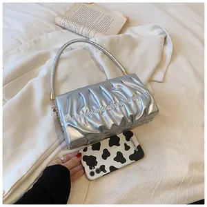Detail der silbernen Falten-Handtasche mit goldenen Ringen und Kuhmuster-Handyhülle