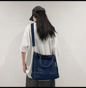 Close-up of dark blue denim tote bag with yellow contrast stitching and metal hooks