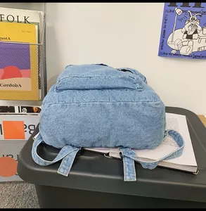 Detail eines blauen Denim-Rucksacks mit Bodenkontur und Nähten auf einem Regal