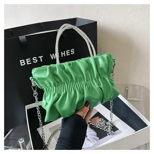 Detail of green ruched cloud bag featuring rhinestone handles and silver chain strap