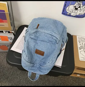 Detailansicht hellblauer Denim-Rucksack mit braunem Lederpatch auf schwarzer Aufbewahrungsbox