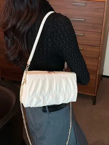 Modische weiße Plissee-Achseltasche mit goldener Kette an einem Modell gezeigt