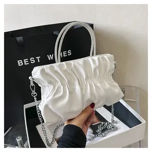 Detail of white pleated cloud bag featuring dual rhinestone handles and silver chain strap